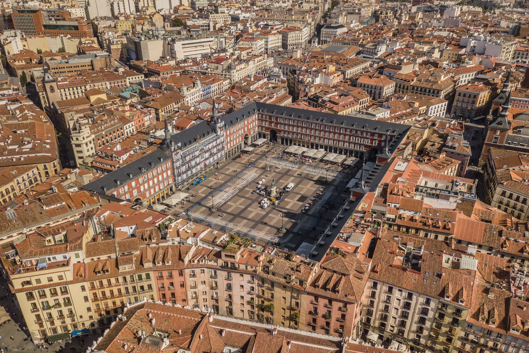 Fotografía aérea de la Plaza Mayor de Madrid llena de terrazas y personas caminando.