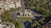 Vista de la Puerta de Alcalá rodeada de tráfico y turistas paseando en un día soleado de verano.