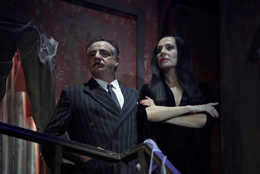 Fotografía de medio cuerpo de los actores Natalia Millán y Javier Navares durante un pase gráfico sobre el escenario del Teatro Calderón. Ella viste clásico vestido negro de Morticia Addams.