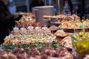 Vista en primer plano de una barra de bar repleta de bandejas con decenas de pintxos y tapas tradicionales españolas atravesadas por palillos.